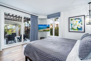 Quarto com uma cama grande, televisão, pintura e vista para o exterior.