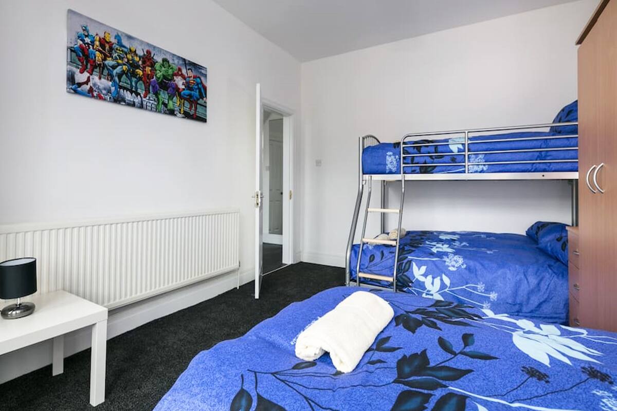 A room with bunk beds, a radiator, a desk with a lamp, and a painting on the wall.