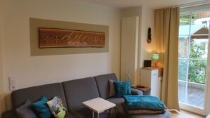 Un saló modern amb un sofà gris, coixinets color turquesa, una taula auxiliar blanca i una obra decorativa a la paret.