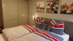 Habitació d'hotel amb un llit gran, dos coixins, un capçal i tres quadres de vaques penjats a la paret.