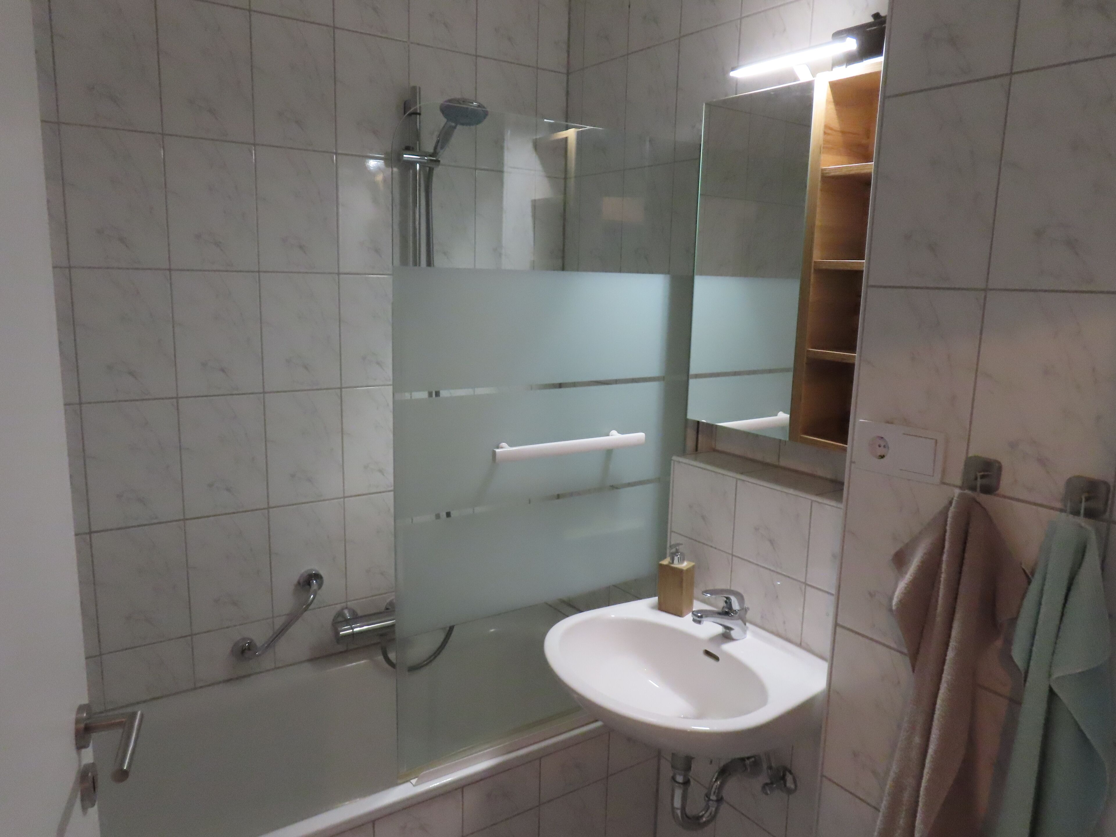 Un baño con cabina de ducha de vidrio, lavamanos y espejo.
