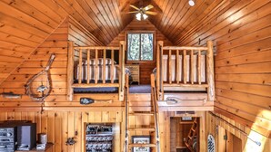 Une cabine avec un lit en mezzanine, un lit superposé en bas, un ventilateur de plafond et une petite fenêtre.