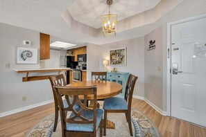 A dining area with a round wooden table, blue upholstered chairs, and a patterned rug. - Spacious and Beachfront Condominium (Saint Simons Island)