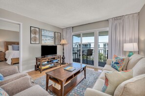 Relax in a stylish room with a sofa, armchairs, and a flat-screen TV, plus a balcony with outdoor seating.