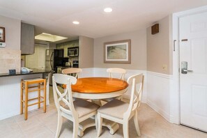 A dining area with a round wooden table and four white chairs.