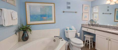 A bathroom with a bathtub, toilet, sink, and vanity.
