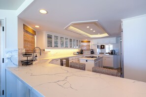 A modern kitchen with white cabinetry, a marble countertop, and built-in appliances. - 1617O: 4  BR, 3  BA House in Oxnard, Sleeps 8 (Oxnard)