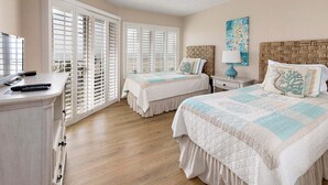 Een hotelkamer met twee bedden, een bureau en een raam met shutters.