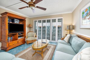 Relax in this inviting living room with a sofa, chair, and coffee table, perfect for unwinding with a TV and a view.