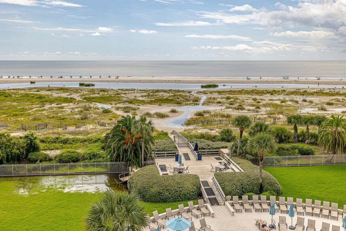 A resort with a pool area, lounge chairs, and a view of the beach and ocean.