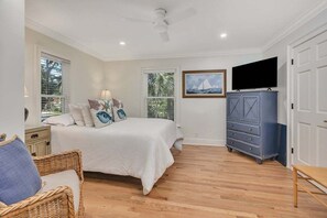 A bedroom with a bed, a dresser, a television, and a window with blinds. - Ocean Views with Swimming Pool. (Saint Simons Island)