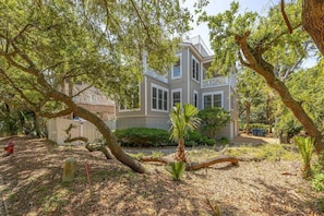 A two-story house with a balcony, surrounded by trees and a garden.