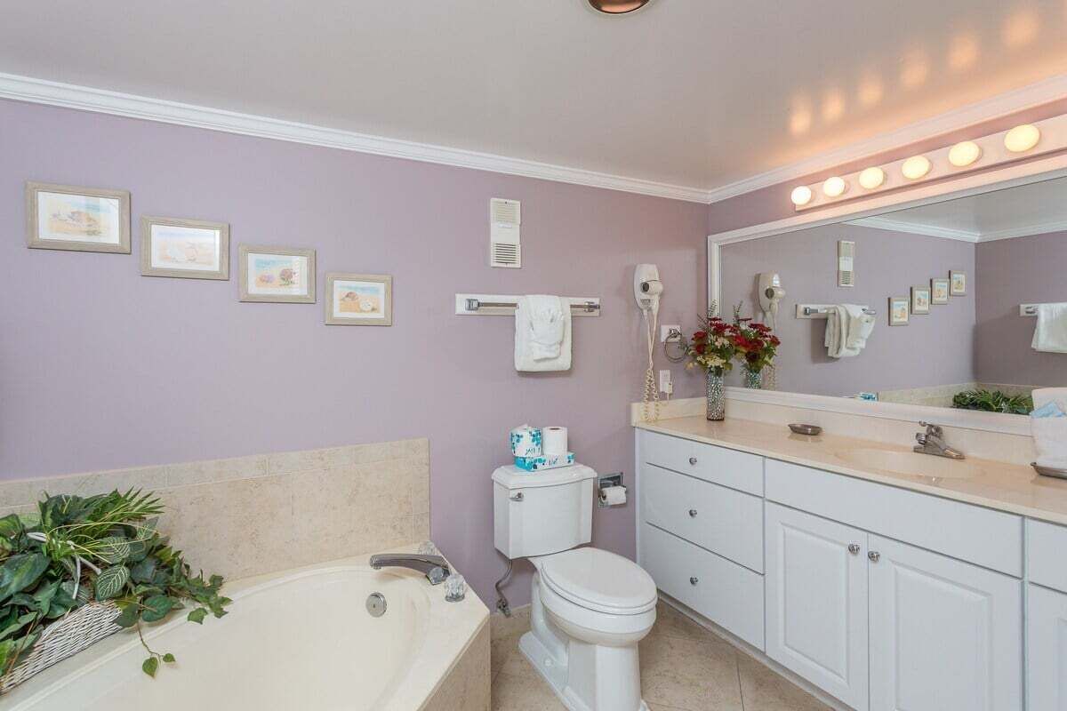 Ein Badezimmer mit Badewanne, Toilette, Waschtisch mit Spiegel und gerahmten Bildern an der Wand.