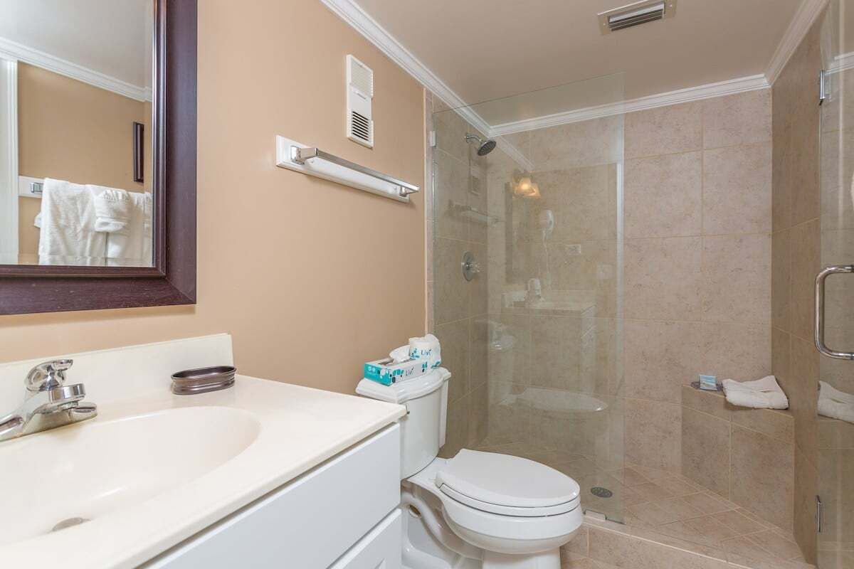 A bathroom with a white sink, a toilet, and a glass-enclosed shower.