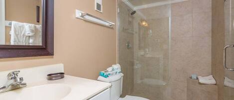 A bathroom with a white sink, a toilet, and a glass-enclosed shower.