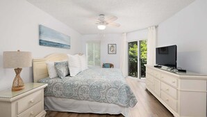 A bedroom with a bed, a nightstand, a dresser, a television, and a ceiling fan. - Oceanfront Condominium with Great Amenities (Saint Simons Island)