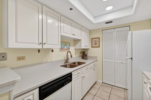 A kitchen with white cabinets, a dishwasher, a double sink, and a coffee maker. - Oceanfront Condominium with Great Amenities (Saint Simons Island)