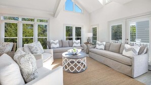 Ein geräumiges Wohnzimmer mit hoher Decke, großen Fenstern und modernem Design.