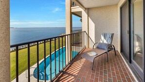 A balcony with a view of the sea, a pool, and a chair. - Oceanfront Condo in the Heart of The Village. (Saint Simons Island)