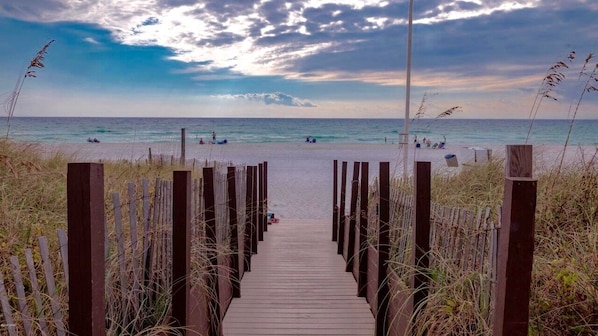 Guests can stroll along the boardwalk to the beach, flanked by lush grasses and wooden posts.