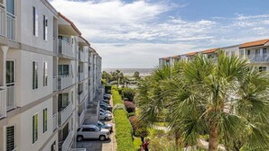 Un hotel de varios pisos con balcones, zona de estacionamiento y vistas al mar.