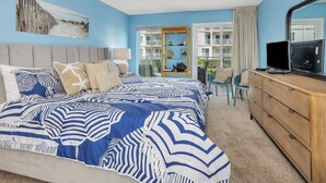 A bedroom with a bed, a dresser, a ceiling fan, and a window with a view of a building. - Spacious Oceanfront Condominium (Saint Simons Island)