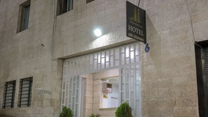 L’entrée d’un hôtel, avec un panneau indicateur, une grille et des plantes en pot.