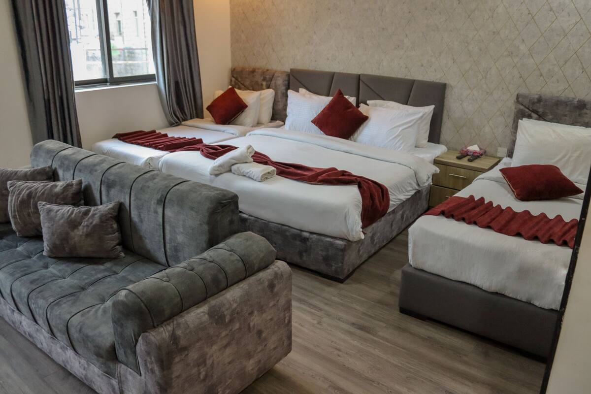 Una habitación de hotel con dos camas, un sofá y una mesita de noche.