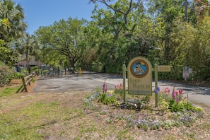 A sign for Ship Watch with a number 1524, surrounded by a garden with various flowers.