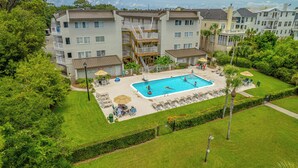 A residential building with a swimming pool, multiple balconies, and a well-maintained lawn.