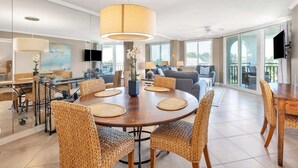 A spacious dining area with a round table, wicker chairs, and a large pendant light. - Oceanfront Condo with Swimming Pool. Ocean View (Saint Simons Island)