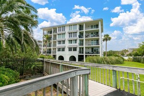 A multi-story hotel with balconies, a wooden deck, and a view of the surrounding greenery. - Oceanfront Condo with Swimming Pool. Ocean View (Saint Simons Island)