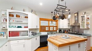 Una cocina moderna con armarios blancos, una isla central y un colgador para ollas.