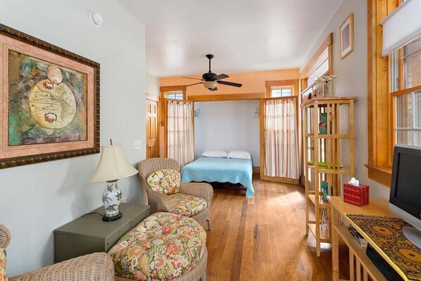 A cozy room with a bed, a chair, a table, and a television. - Home located walking distance to beach and village (Saint Simons Island)