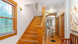 Una escalera de madera con barandilla, que lleva a una habitación con vistas al exterior.