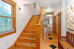 A wooden staircase with a handrail, leading to a room with a view of the outdoors.