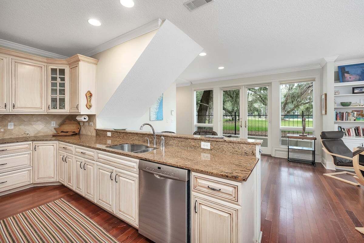 A modern kitchen with white cabinetry, a dishwasher, and a large island with a sink.