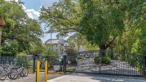 A gated parking area with a bicycle rack, a clear sky, and a building in the background.