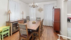 A dining room with a wooden table, chairs, a chandelier, and a cabinet. - Pet friendly, close to the beach, the Pier Village (Saint Simons Island)