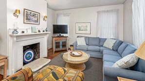 A living room with a fireplace, a sofa, a television, and decorative items on the mantel. - Pet friendly, close to the beach, the Pier Village (Saint Simons Island)