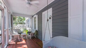 A covered porch with wicker furniture, a hanging swing, and a view of the backyard. - Pet friendly, close to the beach, the Pier Village (Saint Simons Island)