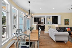 A spacious living room with a dining area, kitchen, and large windows.