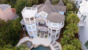 A multi-story house with a pool, surrounded by palm trees and other greenery. - Large Luxury Home with Pool! (Saint Simons Island)
