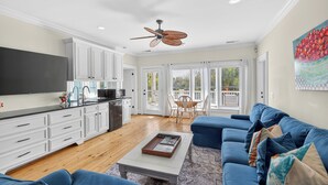 A spacious living area with a kitchen, dining table, and blue sofa. - Large Luxury Home with Pool! (Saint Simons Island)