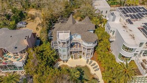 A large, multi-story house with a prominent balcony, a swimming pool, and a covered patio area. - Large Luxury Home with Pool! (Saint Simons Island)