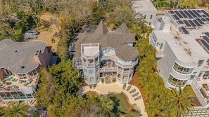 A large, multi-story house with a prominent balcony, a swimming pool, and a covered patio area. - Large Luxury Home with Pool! (Saint Simons Island)