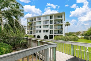 A multi-story hotel with balconies, a wooden deck, and a view of the surrounding greenery.