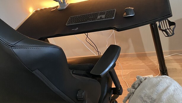 A black gaming chair with adjustable armrests and a high-back design, positioned in front of a black desk with a monitor, keyboard, and mouse. - Room King siz Bed 5 Min Train Arlanda 17 min (Knivsta)