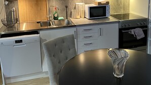 A modern kitchen with white cabinets, a microwave, a dishwasher, and a round dining table with a glass bowl. - Room King siz Bed 5 Min Train Arlanda 17 min (Knivsta)