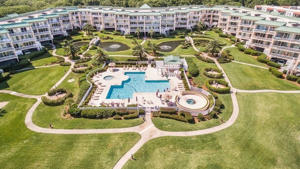 Un hotel con varios pisos, una piscina central y jardines bien cuidados.